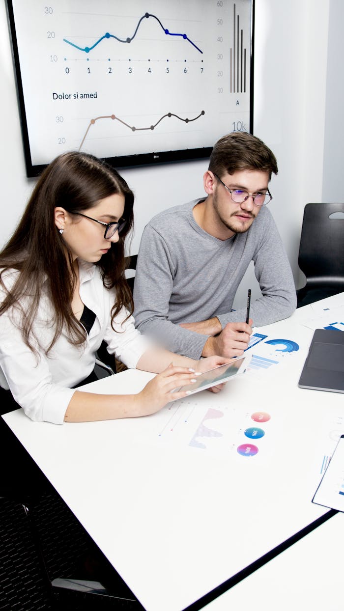 Inicio Two business professionals collaborating on financial analysis with charts and graphs.