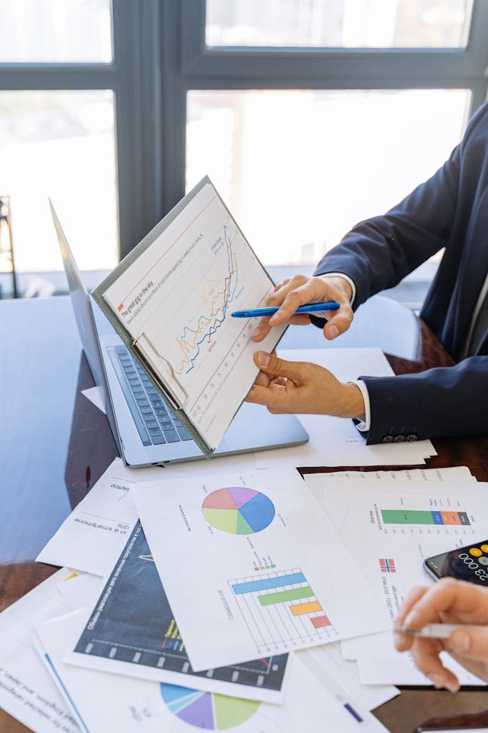 Ofertas de Préstamos Business professionals discussing financial graphs and charts in an office setting.