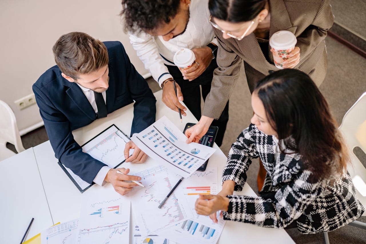 Inicio A diverse team in business attire collaborates over graphs and charts for a successful project.