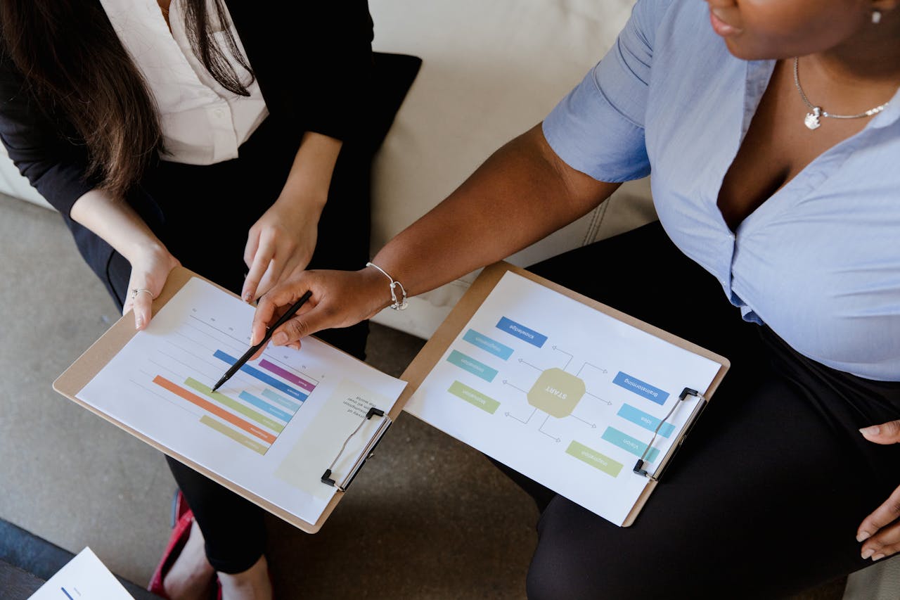 Inicio Two colleagues analyze graphs and reports on clipboards during an office meeting.